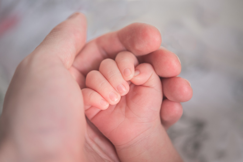 Baby Hand liegt in schützender erwachsener Hand